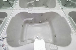 A bathroom with a large bathtub, a toilet, and a sink. - Downtowner Inns Houston (Houston)