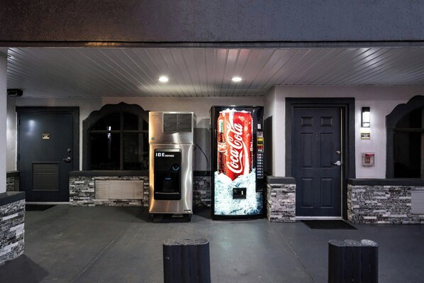 A building entrance with a Coca-Cola vending machine, an ice dispenser, and a door.