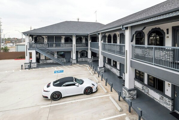 A multi-story building with a parking area and a white sports car parked in the lot.
