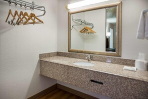 A bathroom with a granite countertop sink, a mirror, and a towel rack. - Motel 6 Opelika, AL (Opelika)