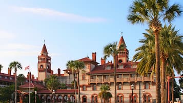 A historic building with multiple towers and arched windows, surrounded by palm trees.