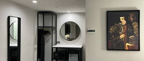 A modern bathroom with a mirror, a round mirror, a sink, and a framed artwork on the wall.