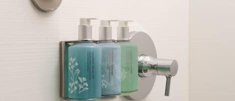 A bathroom with a wall-mounted soap dispenser and a faucet.