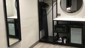 Een moderne badkamer met een grote spiegel, een ronde spiegel en een zwart opbergmeubel met planken.