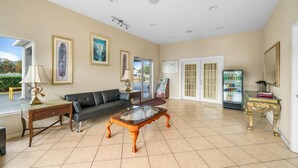 A spacious living area with a sofa, a glass-top coffee table, and a refrigerator. - Rodeway Inn Lake Wales - Winter Haven (Lake Wales)