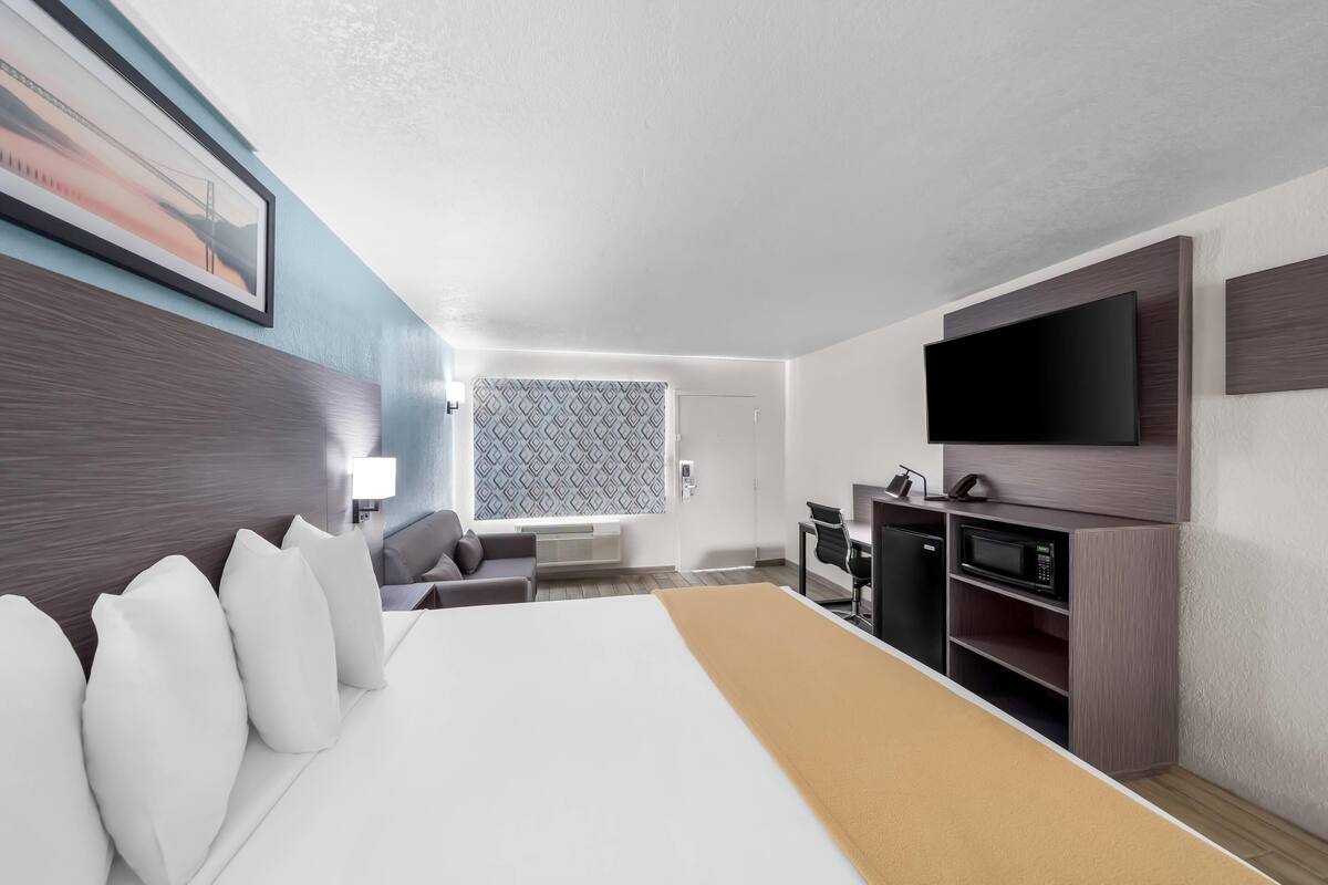 Une chambre d’hôtel avec un grand lit, un bureau avec un ordinateur, une télévision à écran plat et un four à micro-ondes.