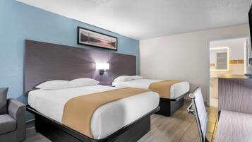 A hotel room with two beds, a desk, a chair, and a bathroom visible through an open door.