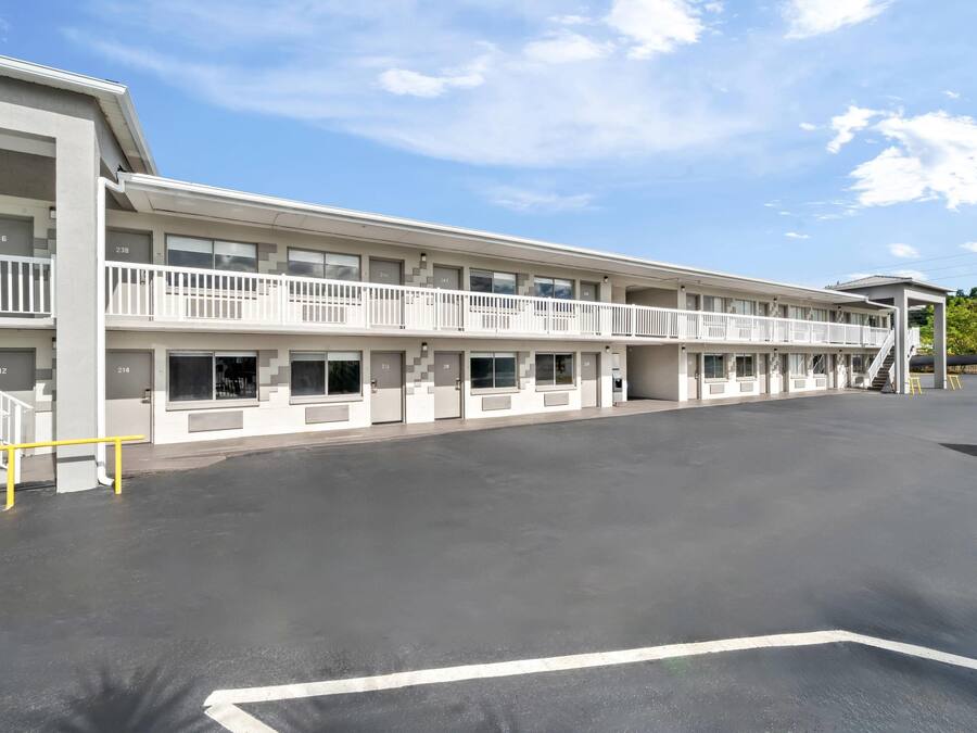 Et motel med to etager, flere balkoner og en parkeringsplads.