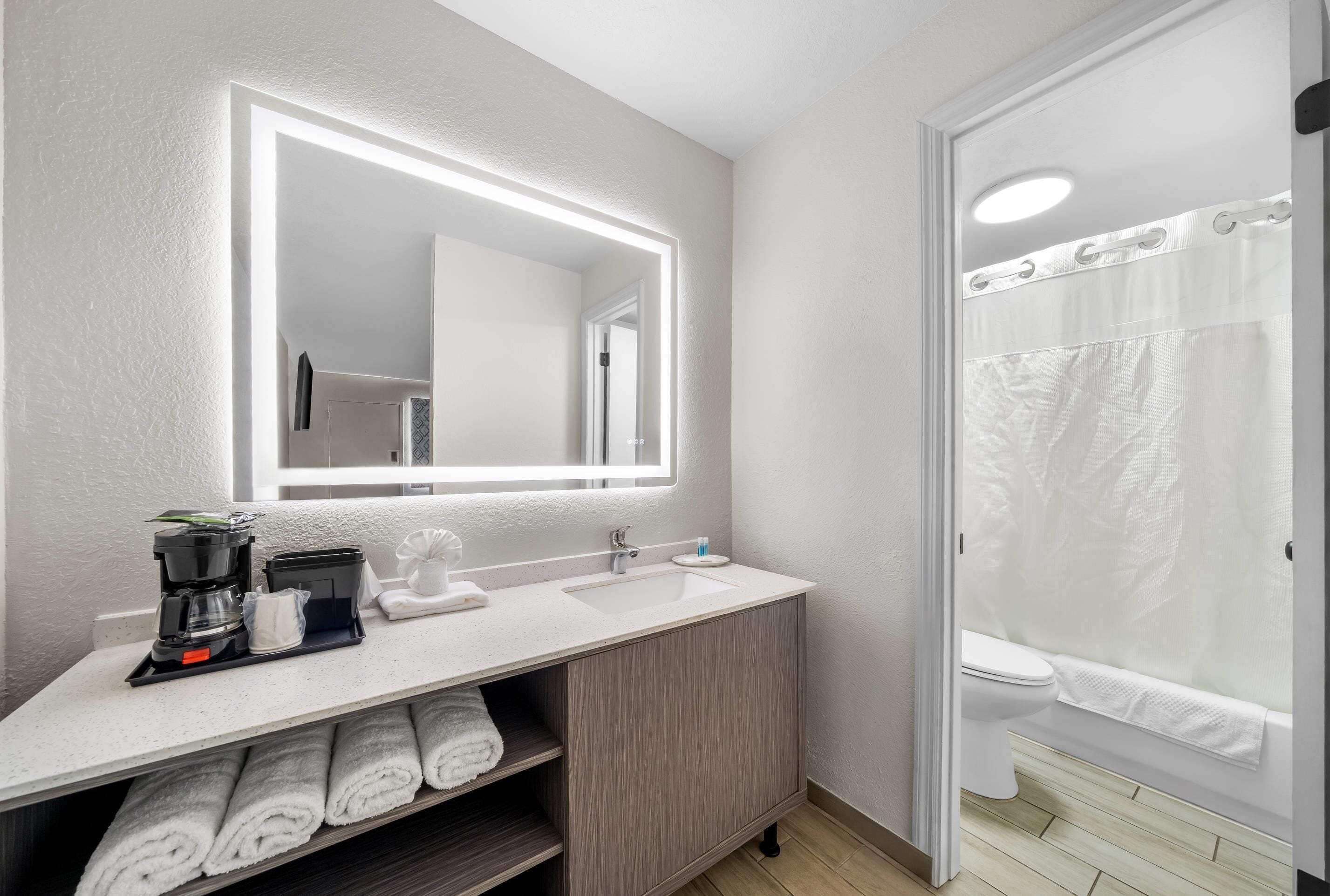 A modern bathroom with a large mirror, a sink, and a shower.