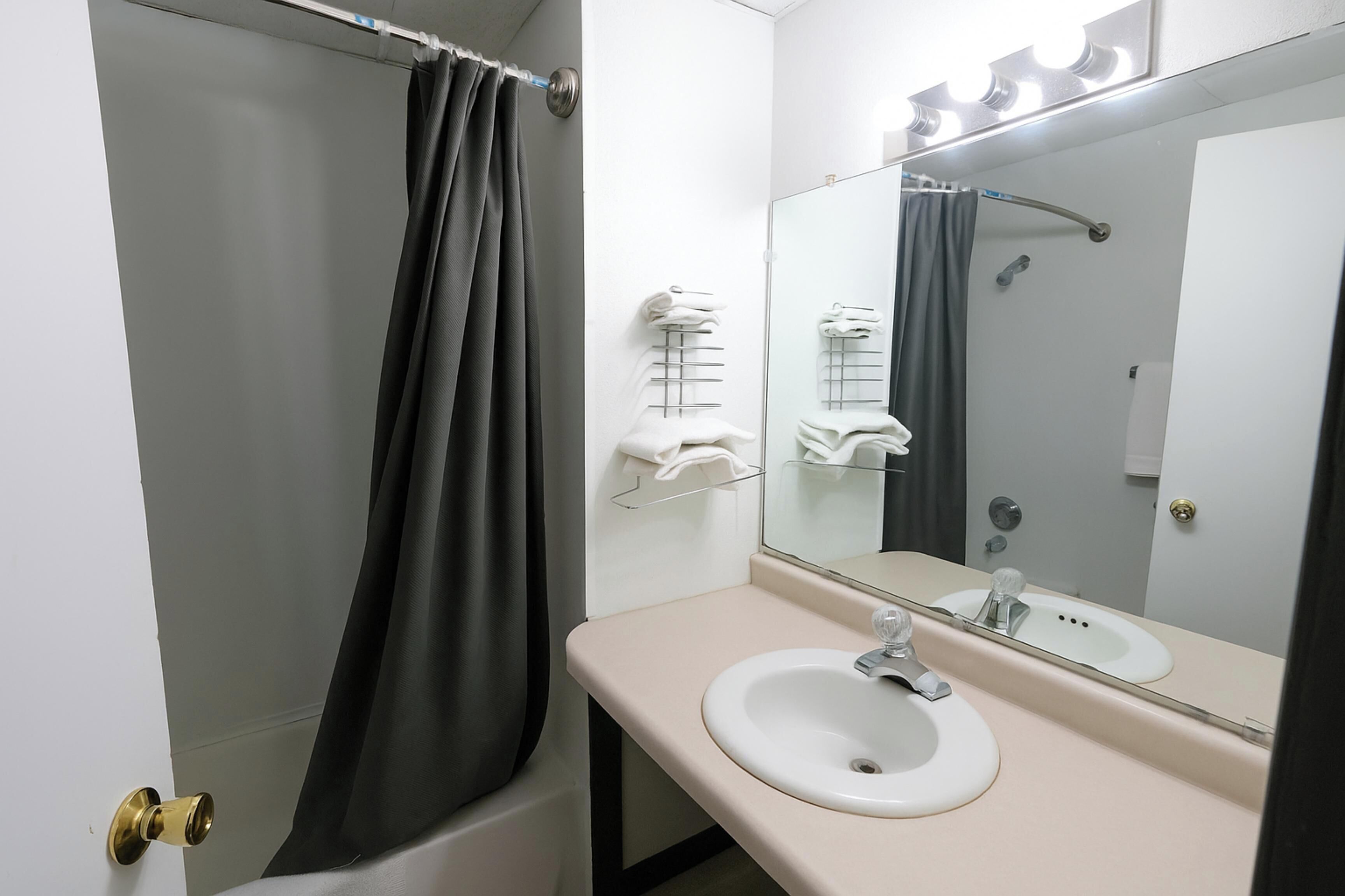 A bathroom with a bathtub, a sink, a mirror, and towel racks.
