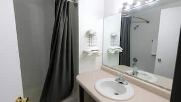 A bathroom with a bathtub, a sink, a mirror, and towel racks.