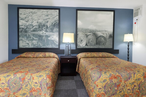 A hotel room with two beds, a nightstand, and two wall-mounted lamps. - OYO Landmark Inn Oskaloosa Near Hwy 63 (Oskaloosa)