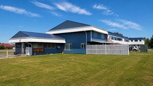 A two-story building with a flat roof and a white fence in front.
