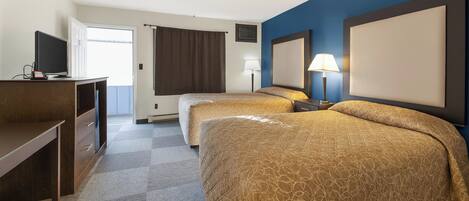 A hotel room with two beds, a desk, a TV, and a window with curtains.
