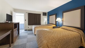 A hotel room with two beds, a desk, a TV, and a window with curtains.