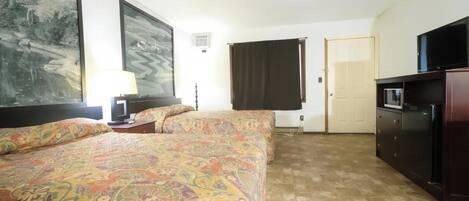 A hotel room with two beds, a television, a desk, and a large painting on the wall.