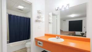 A bathroom with a white toilet, a blue shower curtain, an orange sink, and a mirror.