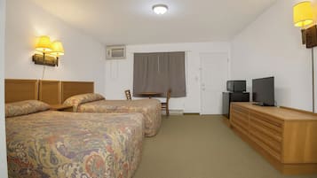 A hotel room with two beds, a desk, a television, and a dresser.
