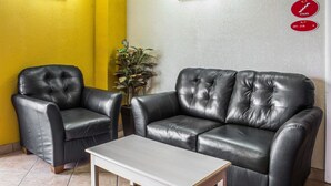 A room with a black leather sofa, a matching armchair, and a small white table. - Econo Lodge Inn & Suites Walnut (Walnut)
