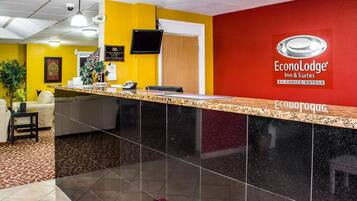 Un mostrador de recepción de hotel con pared roja, encimera negra y un cartel de EconoLodge Inn & Suites.