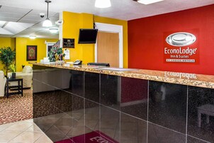 Un mostrador de recepción de hotel con pared roja, encimera negra y un cartel de EconoLodge Inn & Suites.