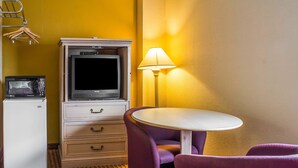 A compact hotel room with a kitchenette, a television, a small table, purple chairs, and a lamp. - Econo Lodge Inn & Suites Walnut (Walnut)