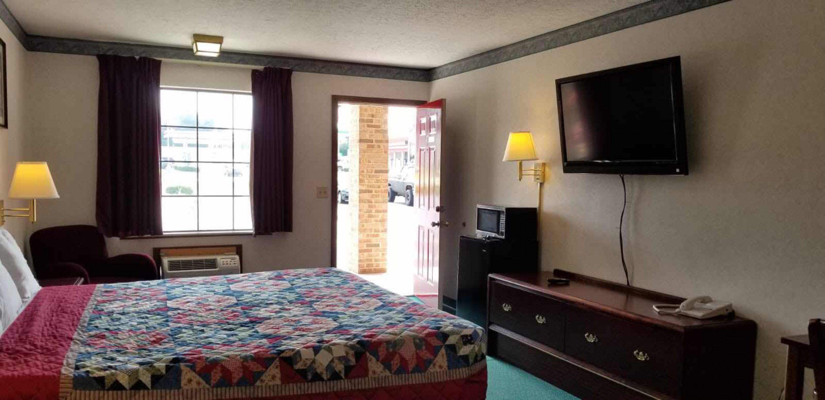 Una habitación de hotel con una cama grande, televisión, escritorio y una silla.