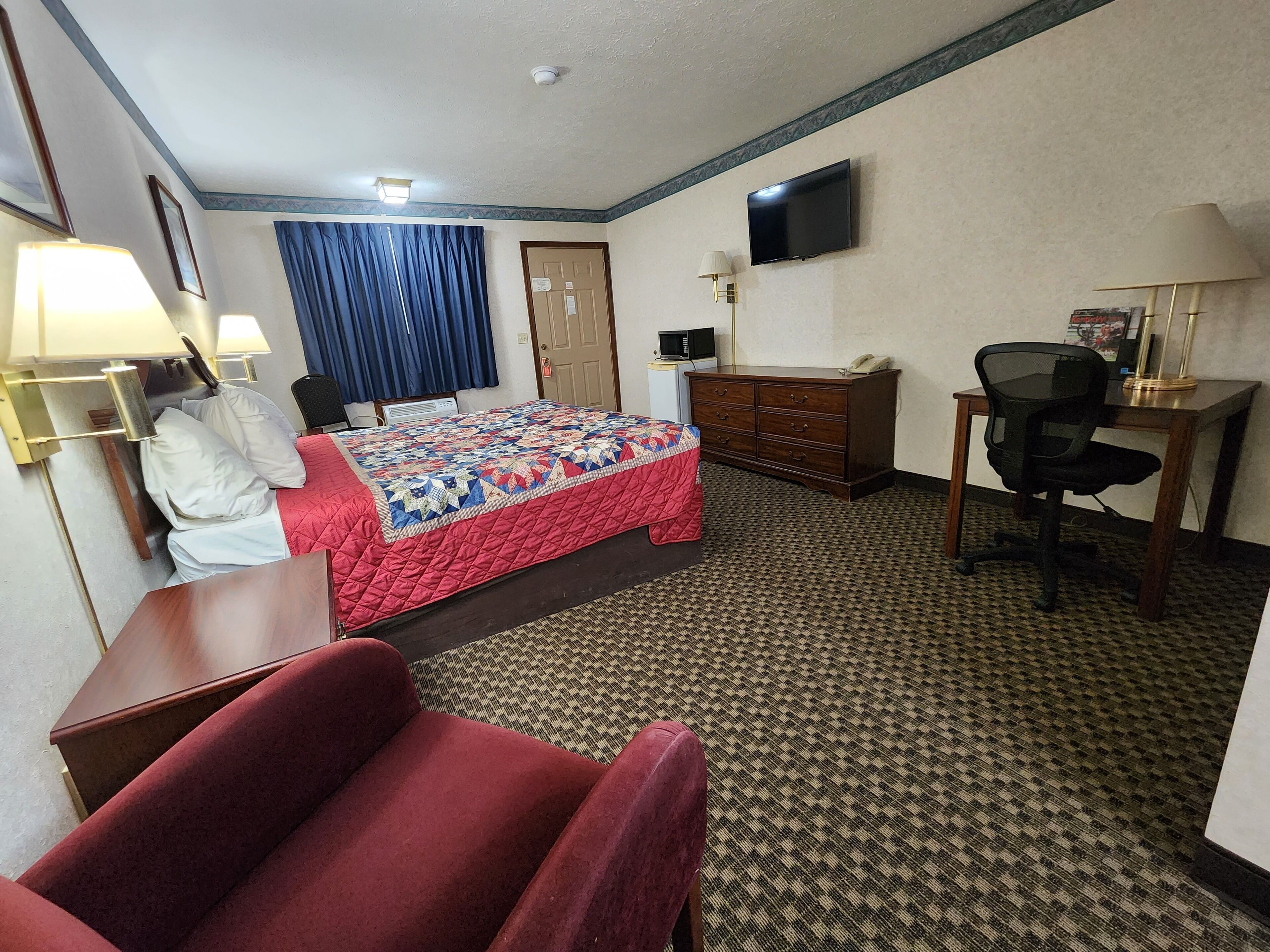 Una habitación de hotel con cama, escritorio, silla y televisión.