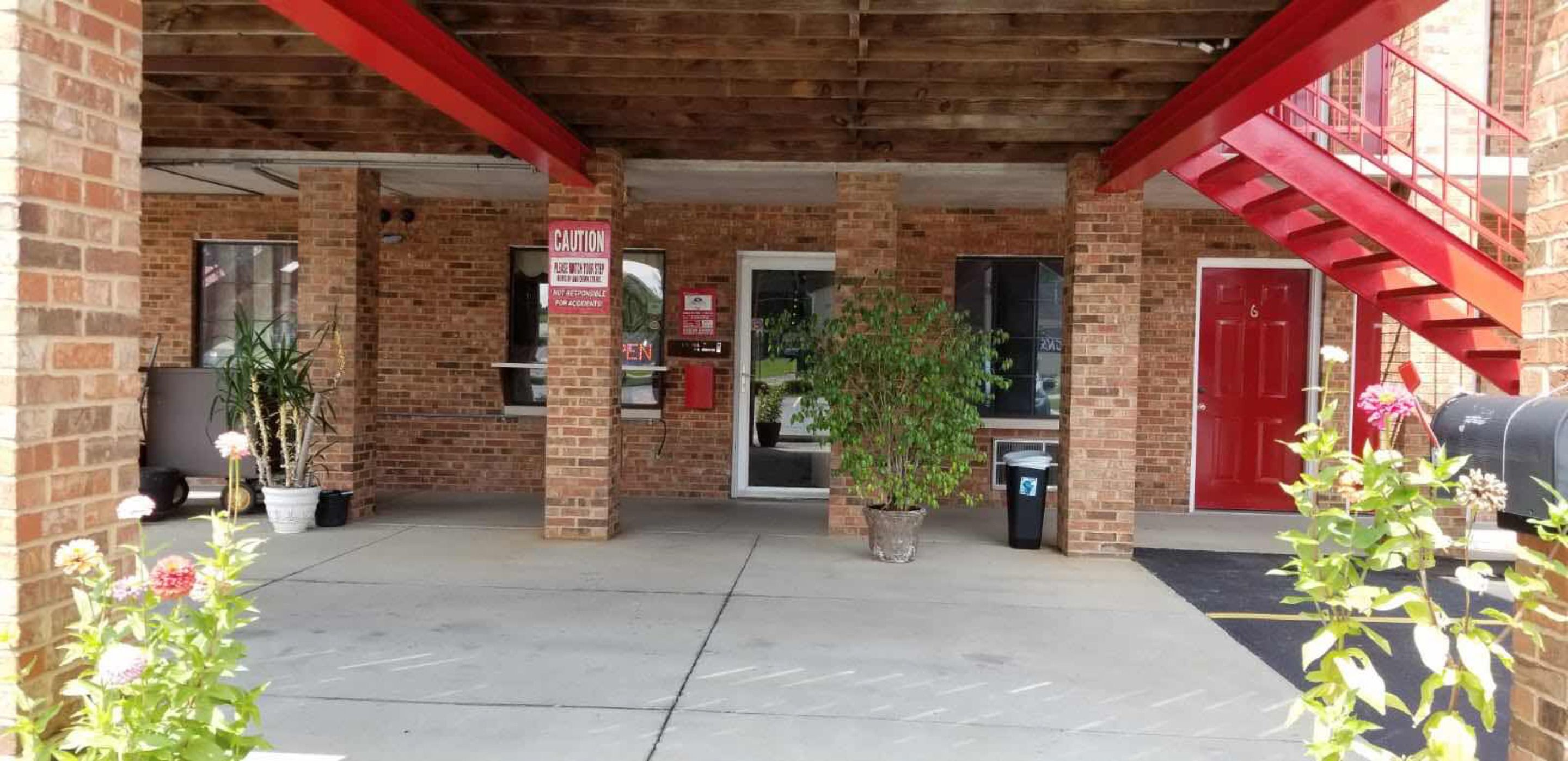 A brick building with a red fire escape, a closed door, and a caution sign.