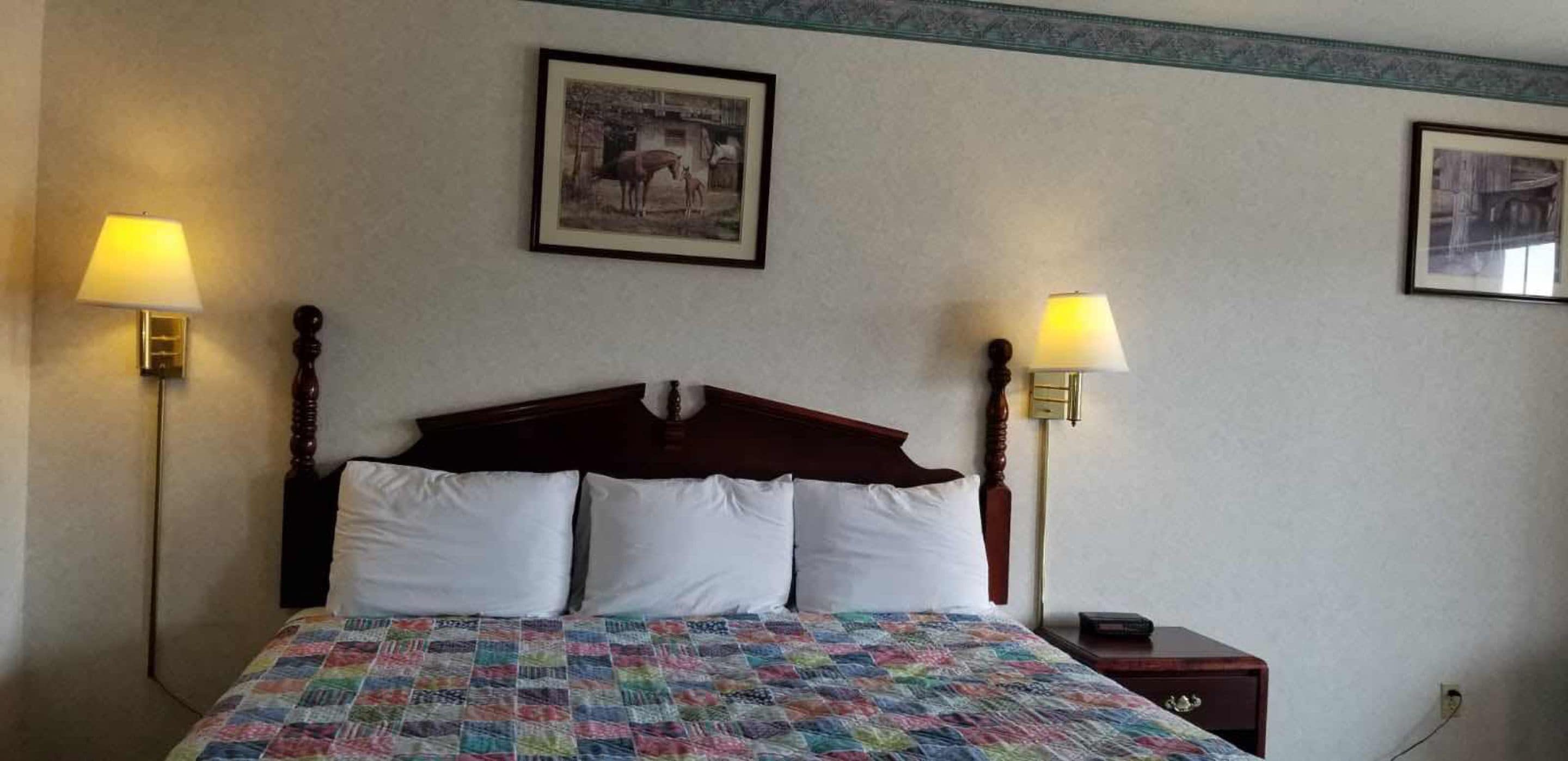 A bed with a wooden headboard, two bedside lamps, and a quilt.