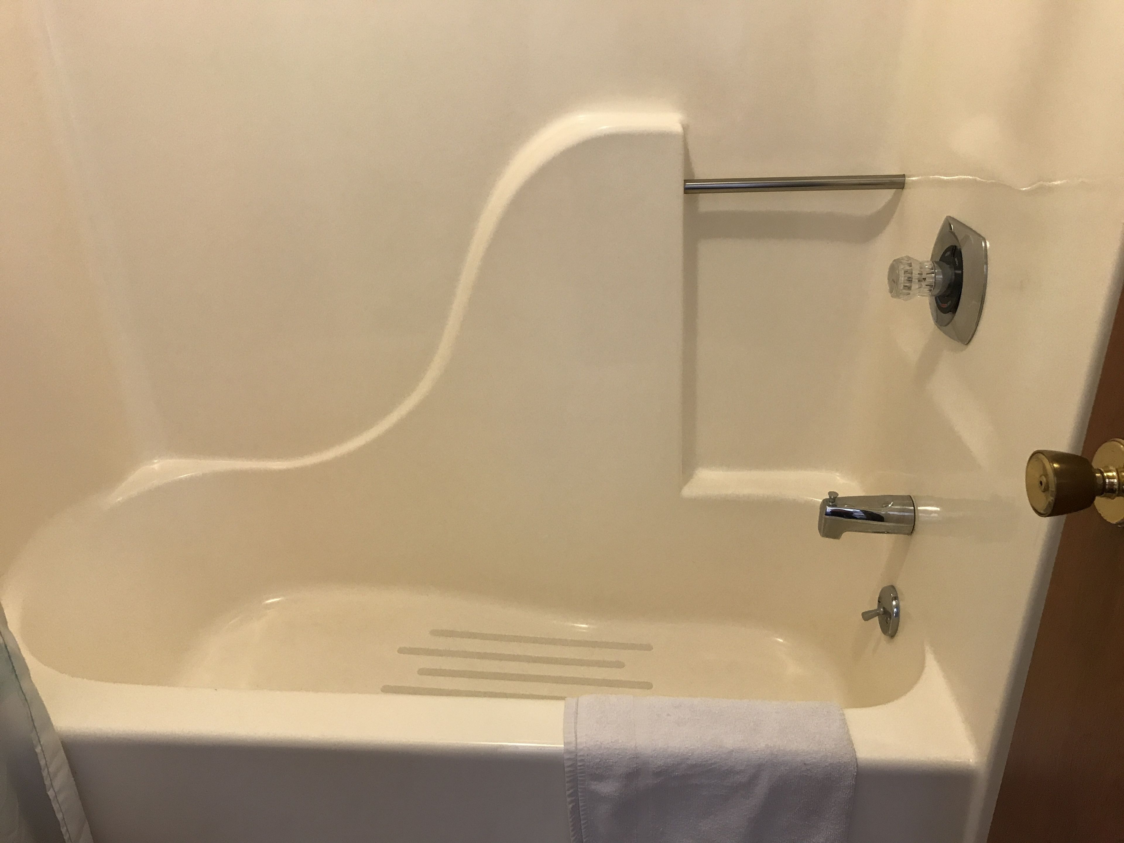 A white bathtub with a single faucet and a towel hanging on the side.