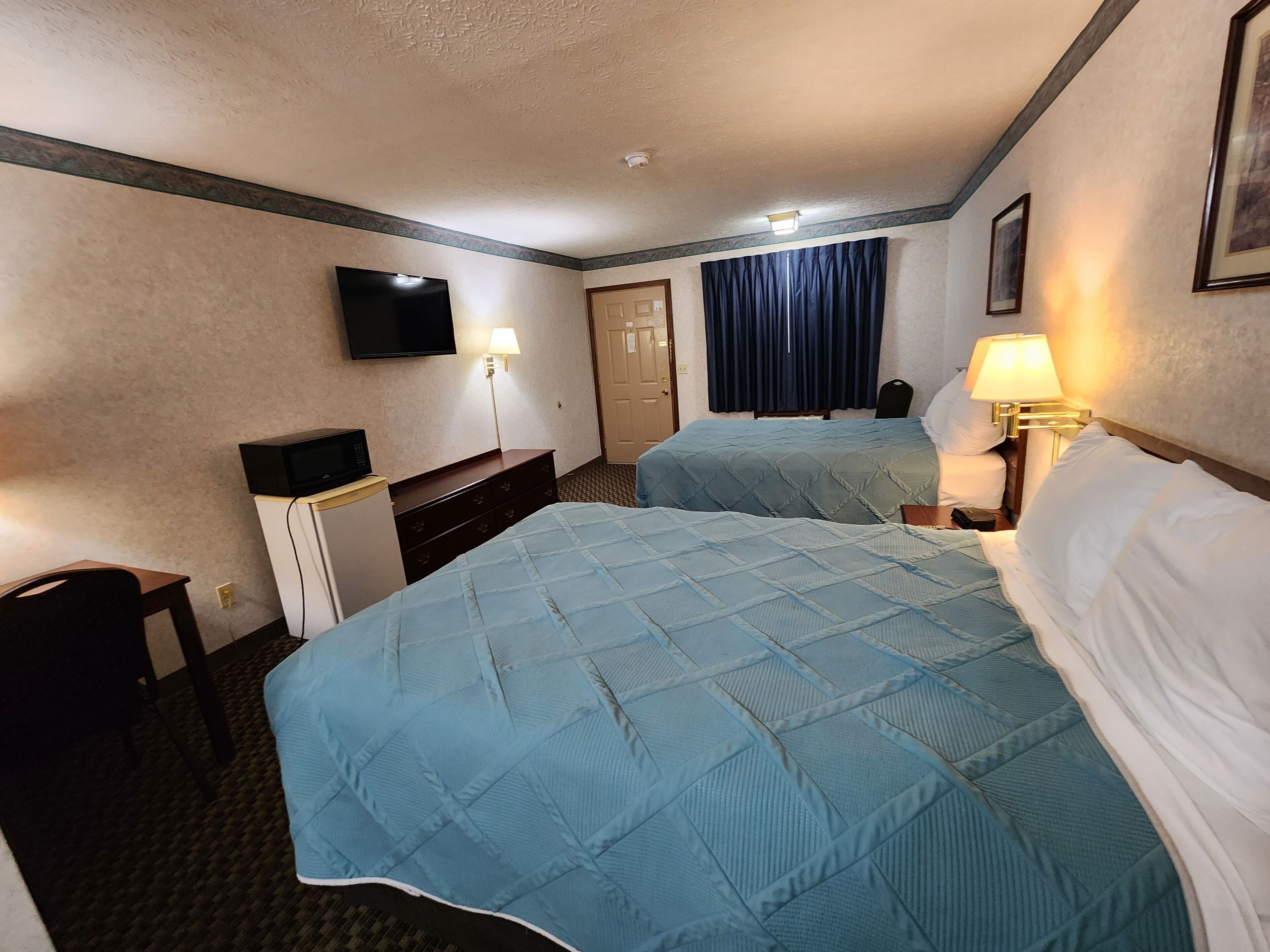 Une chambre d’hôtel avec deux lits, une télévision, un bureau et une chaise.