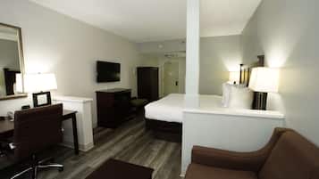 A hotel room with a bed, a desk with a chair, a television, and a mirror.