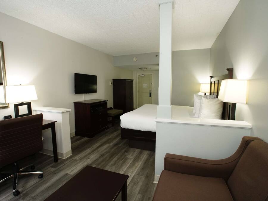 A hotel room with a bed, a desk with a chair, a television, and a mirror.