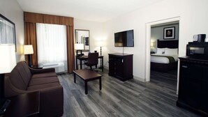 A hotel room with a sofa, a desk, a television, a bed, and a dresser. - Best Western Paramus Hotel & Suites (Paramus)