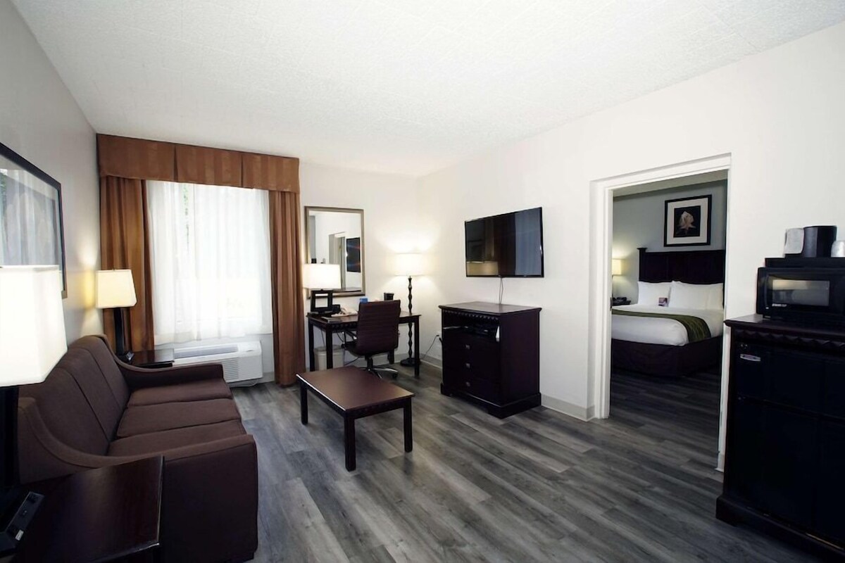 A hotel room with a sofa, desk, TV, and a bed.