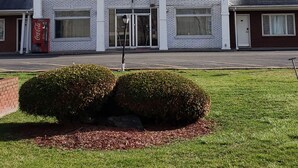 Un edificio de dos plantas con fachada simétrica, ventanas grandes y una entrada central con puerta y puertas dobles.