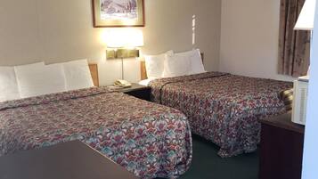 A hotel room with two beds, a framed picture on the wall, a lamp, and a window with curtains.