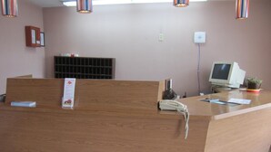 Una recepción con un teléfono, un monitor de computadora y una planta pequeña.