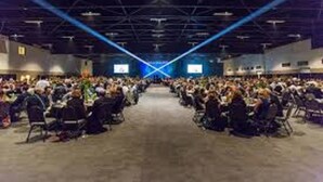 A large indoor venue with rows of chairs facing a stage, equipped with a sound system and a large screen. - Super 8 by Wyndham Millbury/Toledo (Millbury)