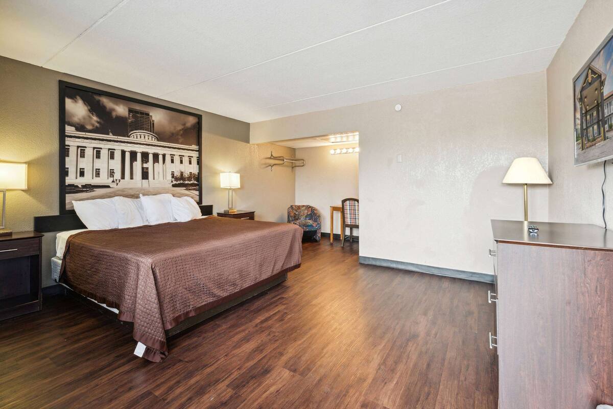 Een hotelkamer met een groot bed, een nachtkastje, een bureau, een stoel en een lamp.