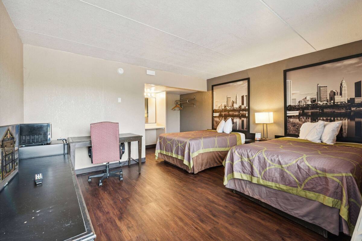 Een hotelkamer met twee bedden, een bureau, een stoel en een televisie.