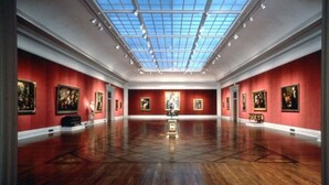 A spacious art gallery with red walls and a high ceiling with skylights. - Super 8 by Wyndham Millbury/Toledo (Millbury)
