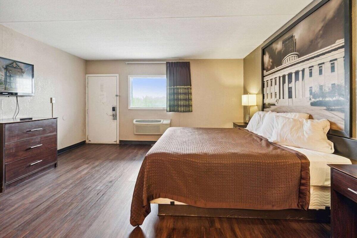 Een hotelkamer met een bed, een bureau, een stoel, een televisie, een raam en een deur.