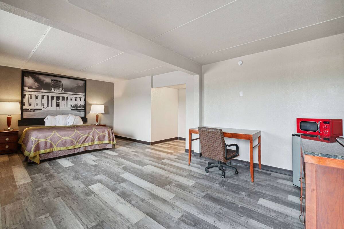 Een hotelkamer met een bed, bureau, stoel en een magnetron.