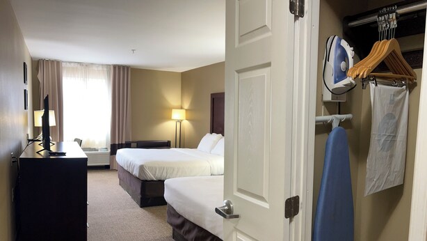 A hotel room with two beds, a desk with a computer, a lamp, and a hanging clothes rack with a towel. - Days Inn & Suites by Wyndham Manheim Lebanon (Manheim)