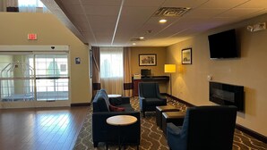 A hotel lobby with a seating area, a fireplace, a television, and a desk with a computer. - Days Inn & Suites by Wyndham Manheim Lebanon (Manheim)