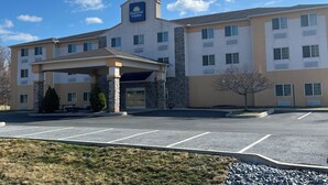 A Days Inn & Suites building with a covered entrance, multiple windows, and a parking lot. - Days Inn & Suites by Wyndham Manheim Lebanon (Manheim)