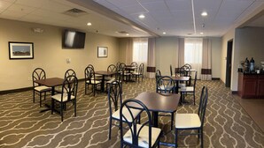 A conference room with multiple tables and chairs, a flat-screen TV mounted on the wall, and a patterned carpet. - Days Inn & Suites by Wyndham Manheim Lebanon (Manheim)