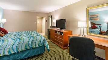 A hotel room with a bed, a desk, a chair, a television, and a mirror.